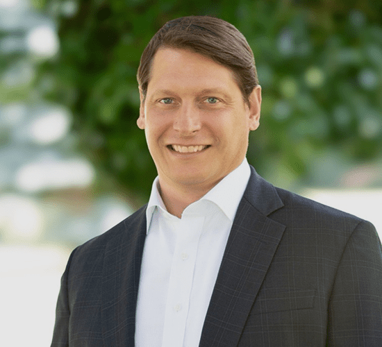 Smiling man in suit with blurred background.